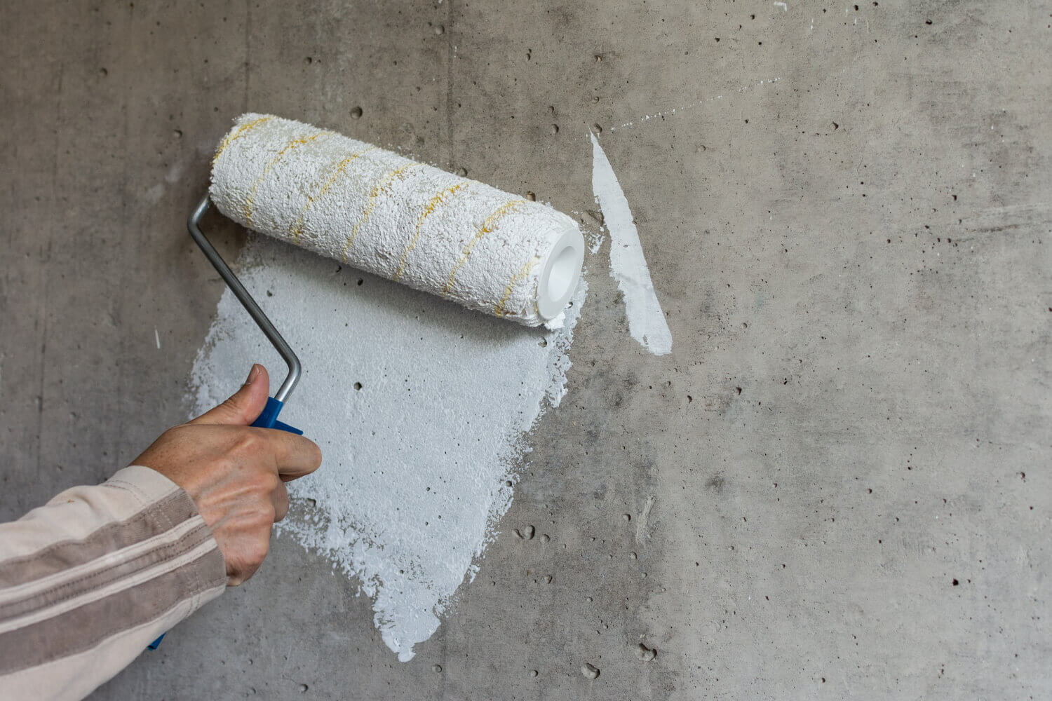painter-paints-concrete-wall-with-white-paint-male-hand-with-paint-roller-for-painting-wall (1) (1)